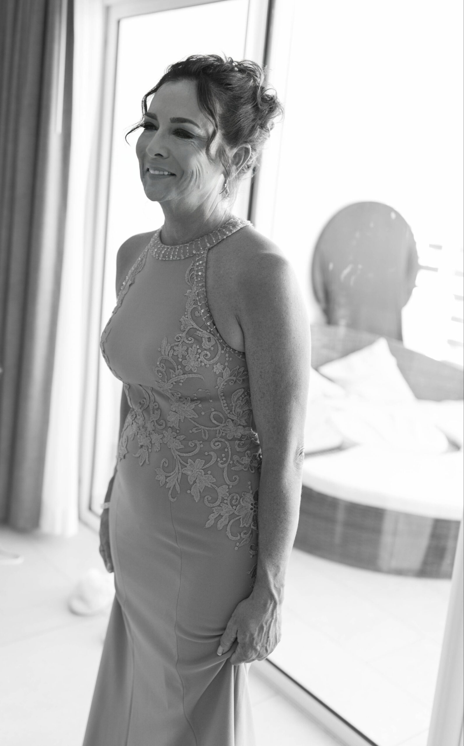 Black and white photo of the mother of the bride smiling to something off-camera and wearing the Vivienne Earrings by Dune Jewelry.