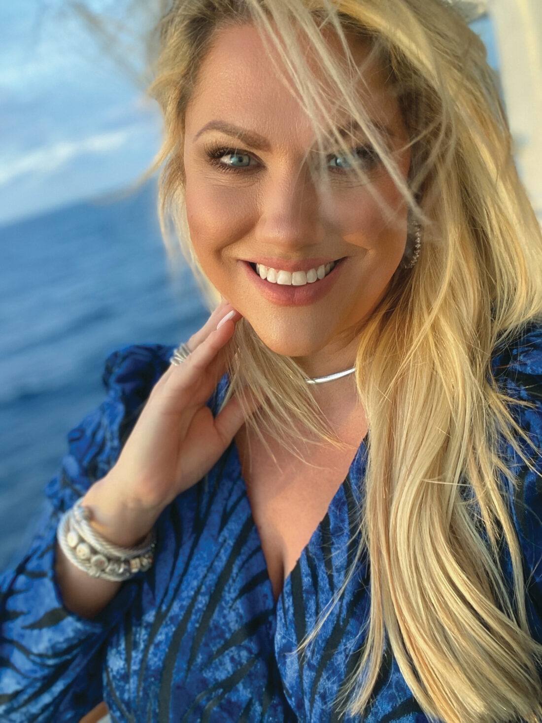 Headshot selfie of Christine Kestaloo wearing sterling silver jewelry on a cruise ship with the ocean behind her.