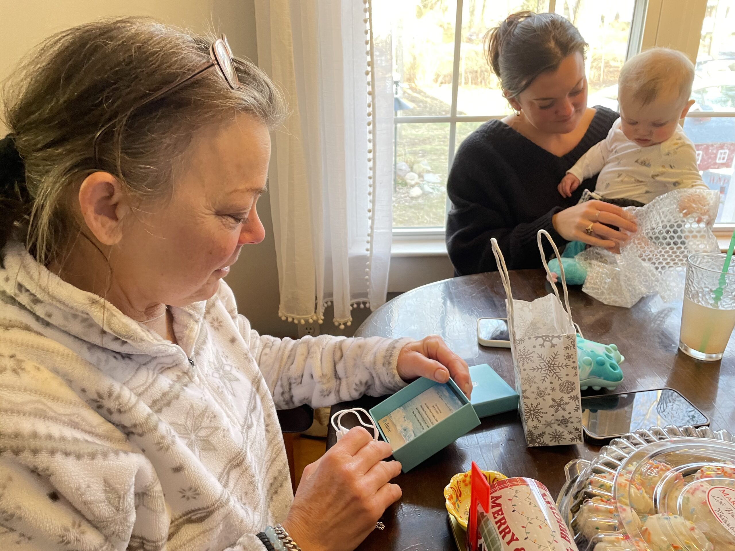 Family sitting at table opening up jewelry gifts from Dune Jewelry.