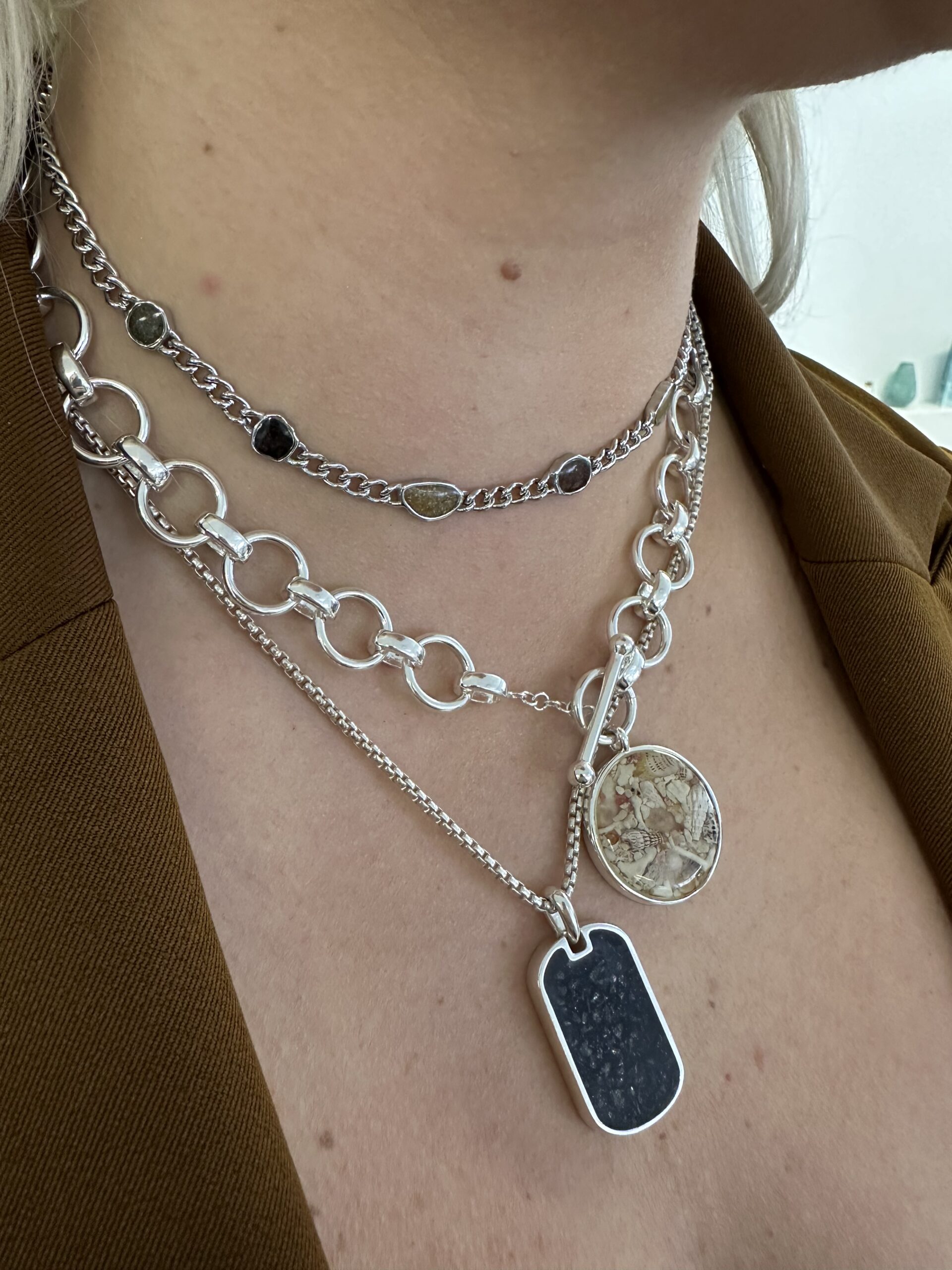 Sterling silver necklaces from Dune Jewelry layered on neck, including the Mediterranean necklace, close-up shot.