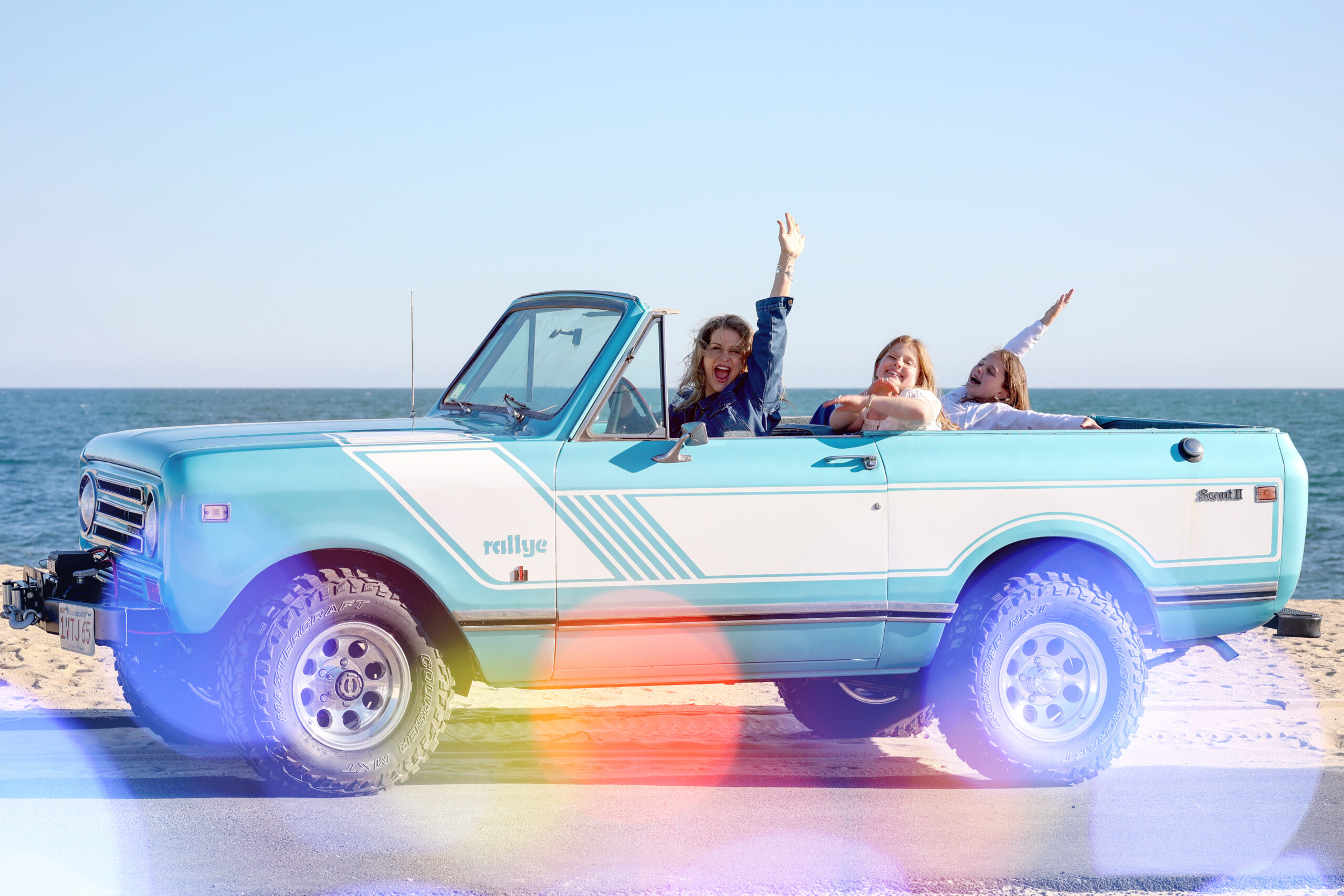 Holly, Dune Jewelry's founder and CEO, and her two daughters in a light blue truck driving in Cape Cod. Mother's Day Jewelry mom retailers header image.