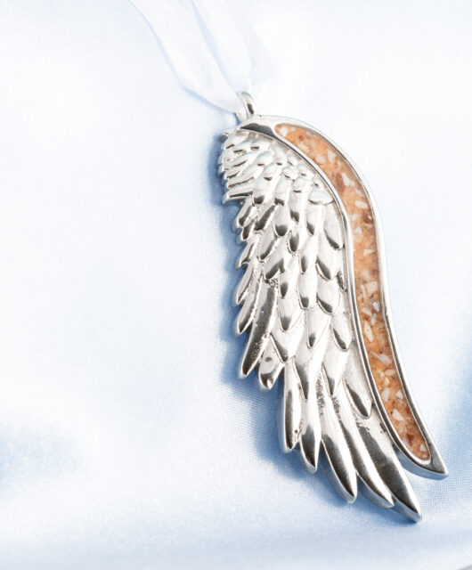 Angel wing ornament with ashes, shells, and rocks by Dune Jewelry