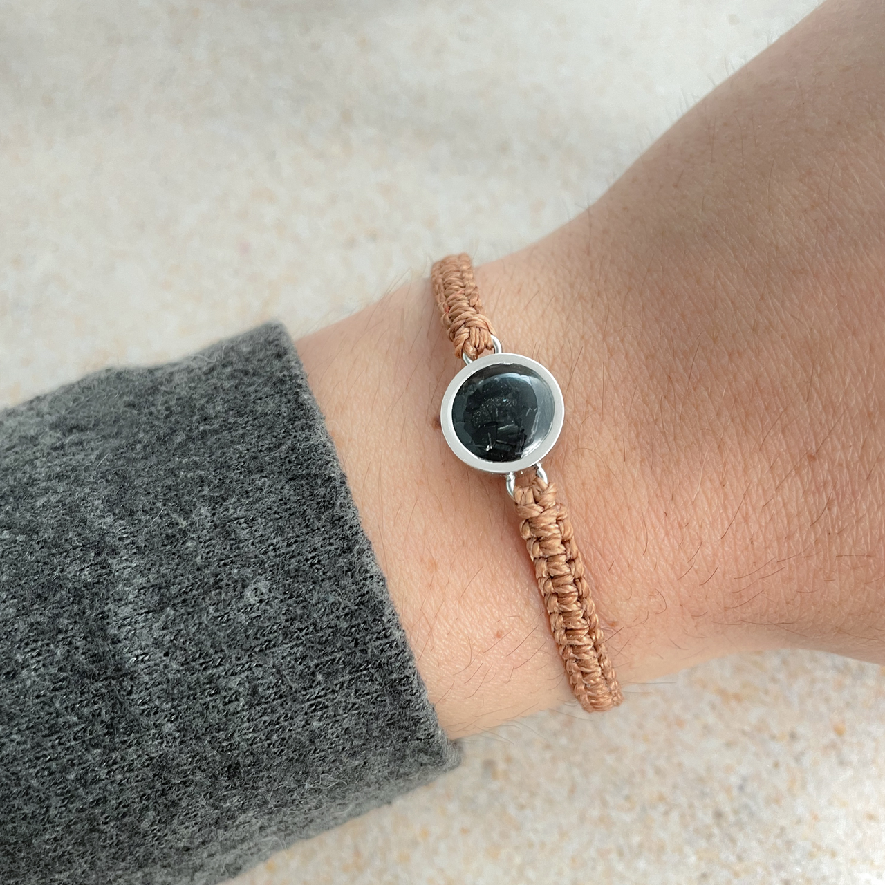 Copper bracelet made with hand-wrapped plastic cord and a circular pendant made with earth elements and stainless steel.