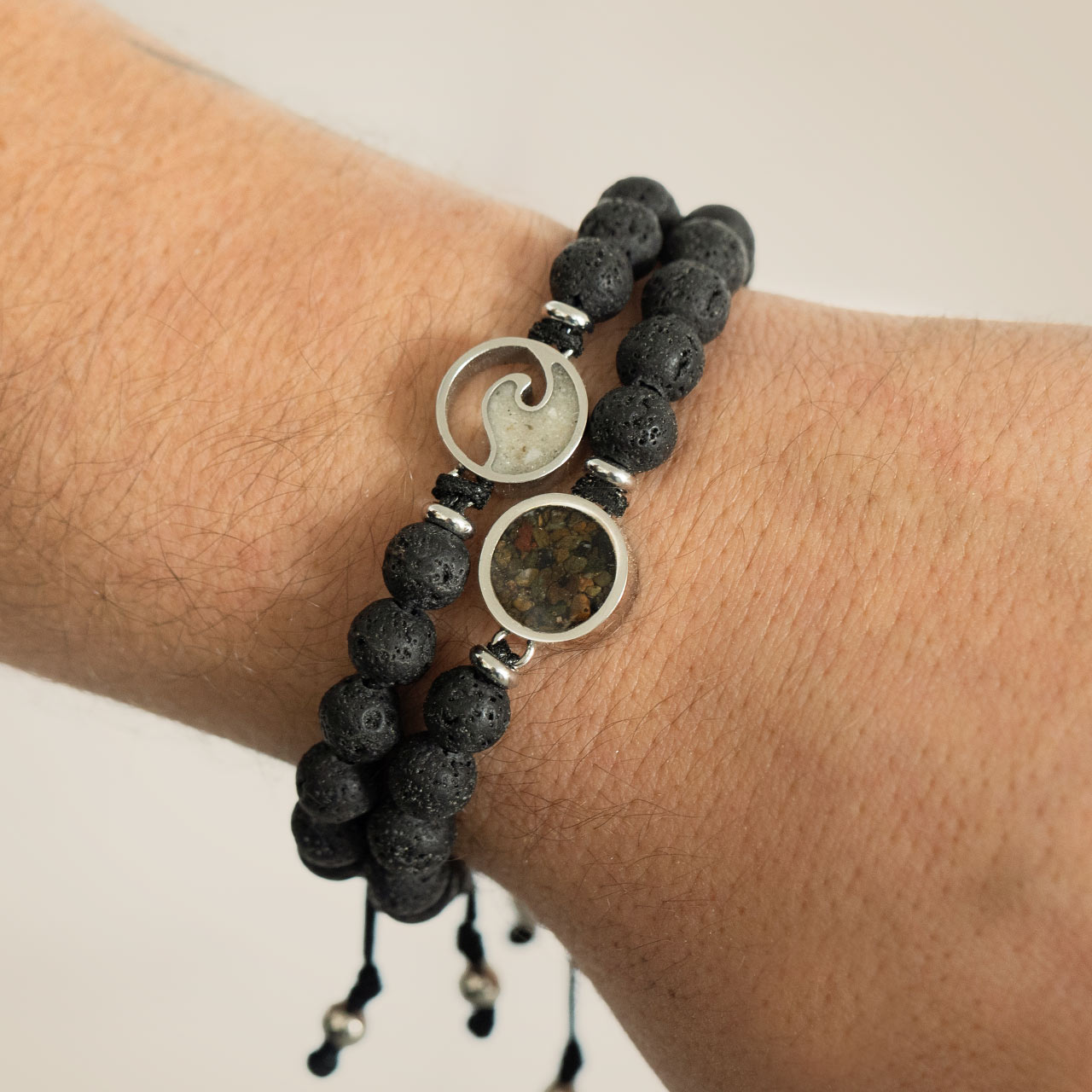 Men's adjustable beaded bracelet with stainless steel wave setting and black lava beads. Rugged masculine jewelry, customizable with sand or earth elements. 